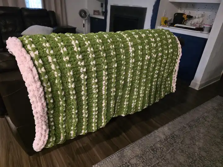 Customer-made chunky knit blanket in green and white stripes with pink edging