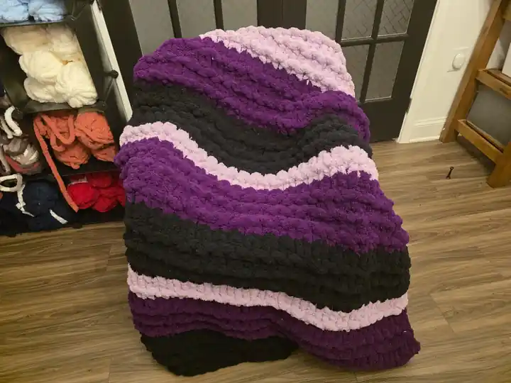 Customer-made chunky knit blanket in purple, black, and pink stripes